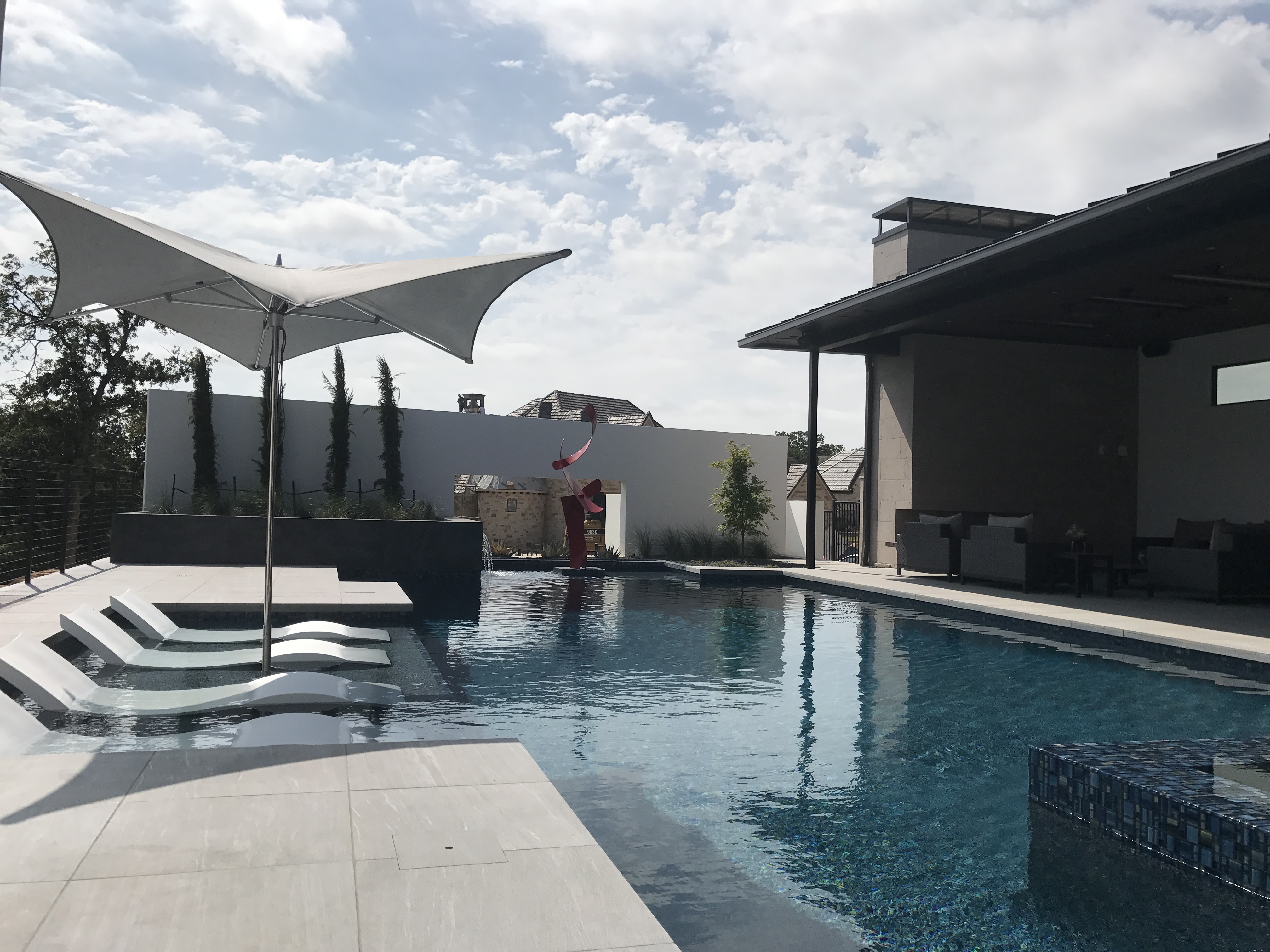 A Chodak Design project — modern pool with shade sail and lounge seating.